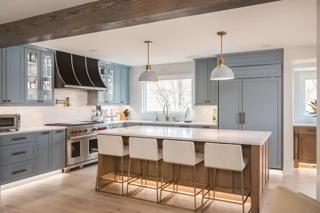 Vienna, VA kitchen with blue-gray cabinets, a reclaimed wood ceiling beam, black and brass range hood and white island stools