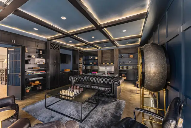 Finished lower level with a coffered blue ceiling, built-in shelving and a leather chesterfield sofa