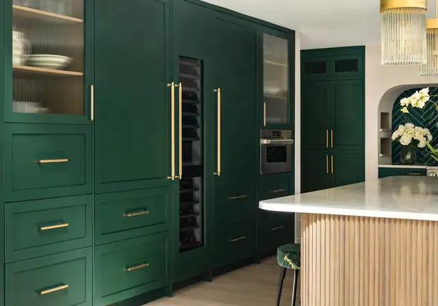 Potomac, MD kitchen with deep green cabinetry, brass pulls, a built-in wine column and a fluted wood island