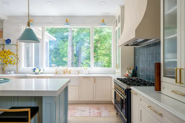 French-style kitchen with white cabinets, blue glass pendants, a blue range and a blue tile backsplash